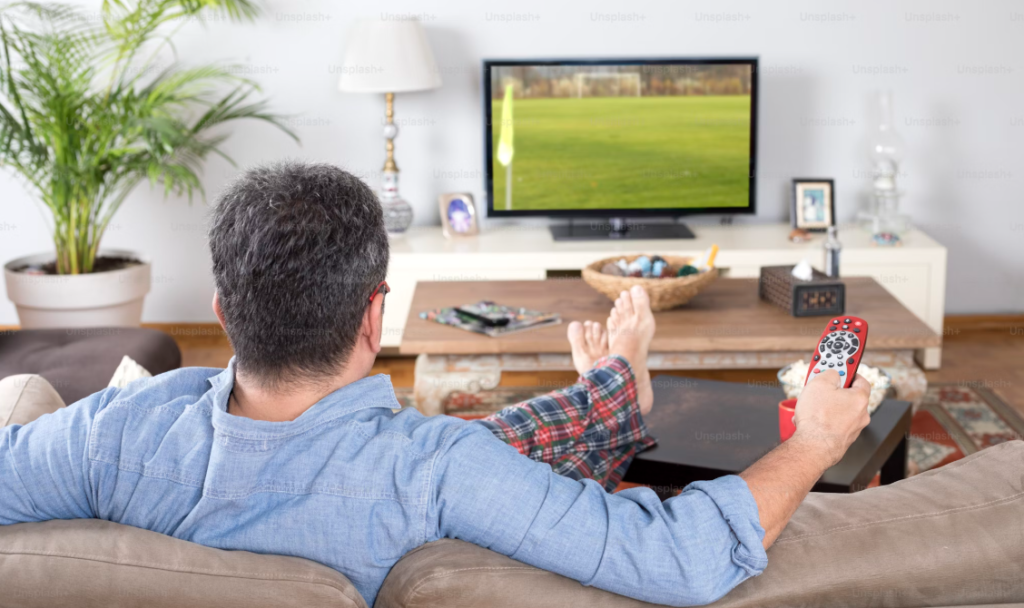 a man sitting on a couch watching a television